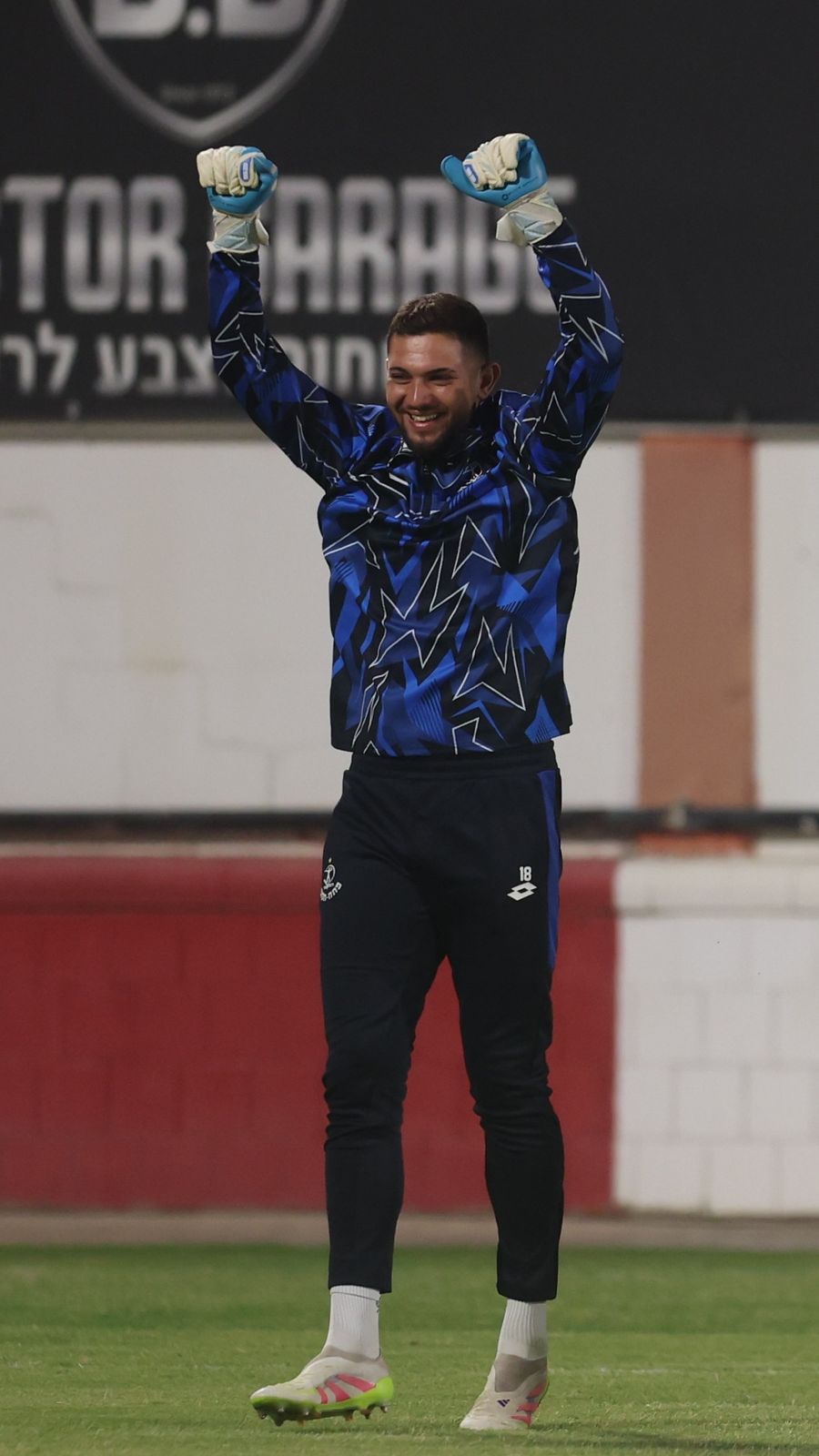 A goalkeeper is celebrating with arms outstretched after a match
