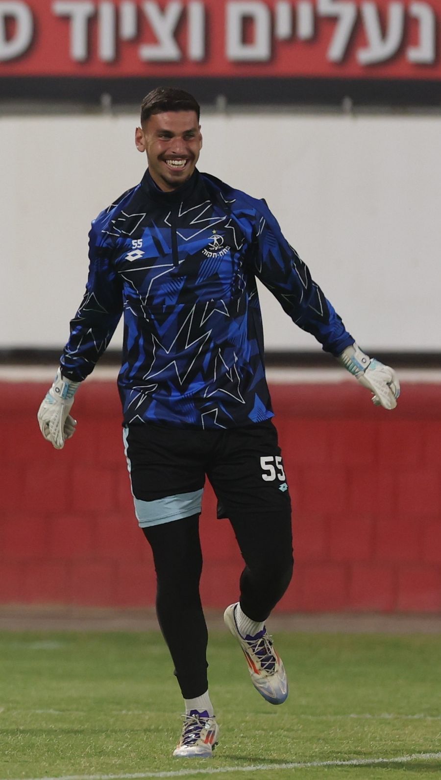 A footballer is smiling and posing for the camera