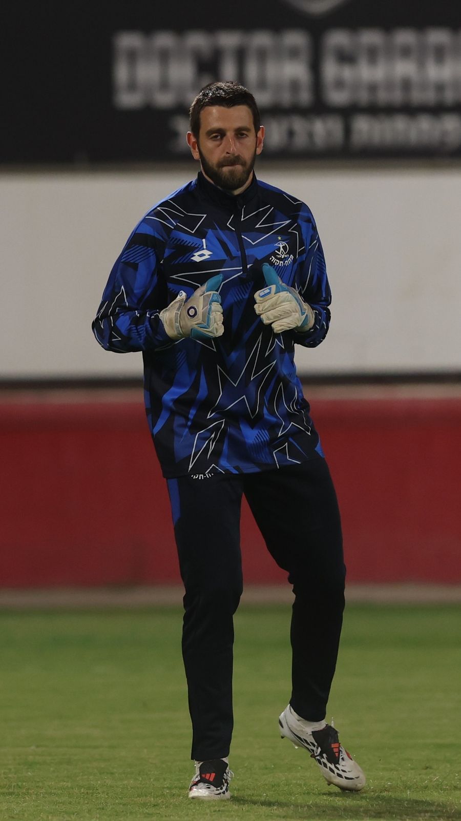 Omer Katz (Hapoel Petah Tikva) is lightning bolt design stands with hands clasped in front, looking to the right