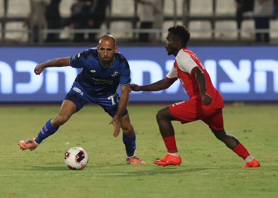 Yazen Nassar (Hapoel Petah Tikva) is preparing to pass the ball as Mathew Anim Cudjoe (Bnei Sakhnin) is attempting to block the ball
