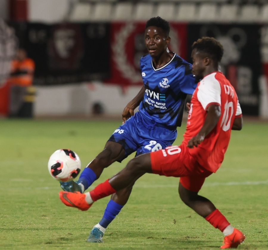 A footballer strikes the ball with his right foot