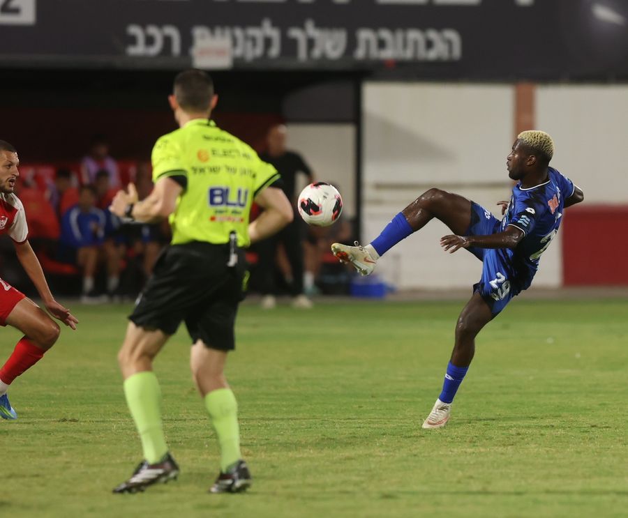 A footballer strikes the ball with his right foot