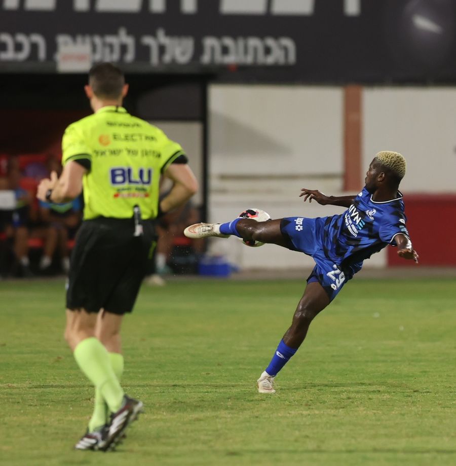 A footballer strikes the ball with his right foot