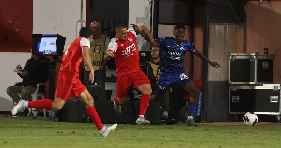 A footballer jumps to challenge the ball