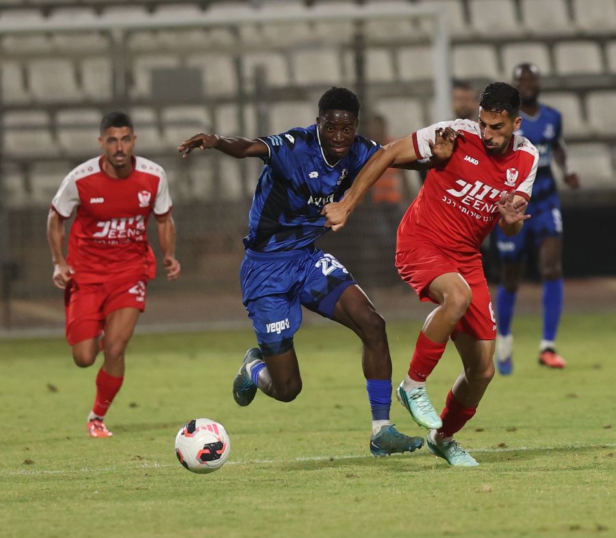 Ilay Hajaj (Bnei Sakhnin) runs and attempting to shield the ball from the opponent as Karim Kimvuidi (Hapoel Petah Tikva) runs and trying to get the ball