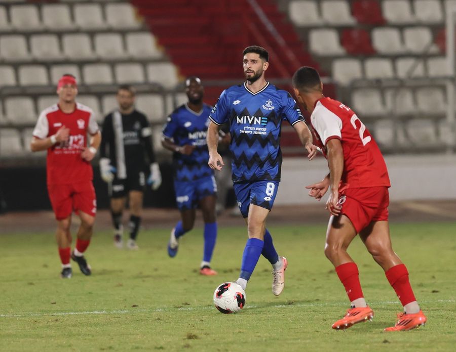 A footballer controls the ball with his right foot