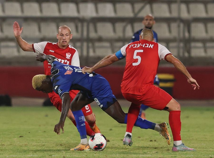 A footballer is being tackled by an opponent