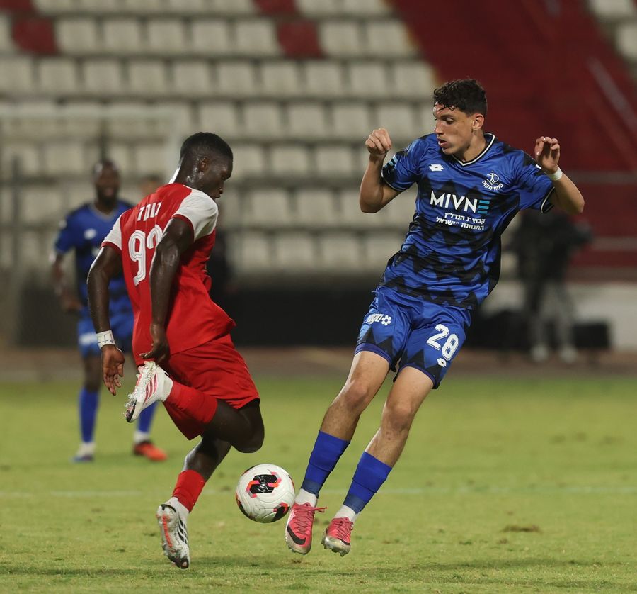 A Bnei Sakhnin player is attempting to kick the ball