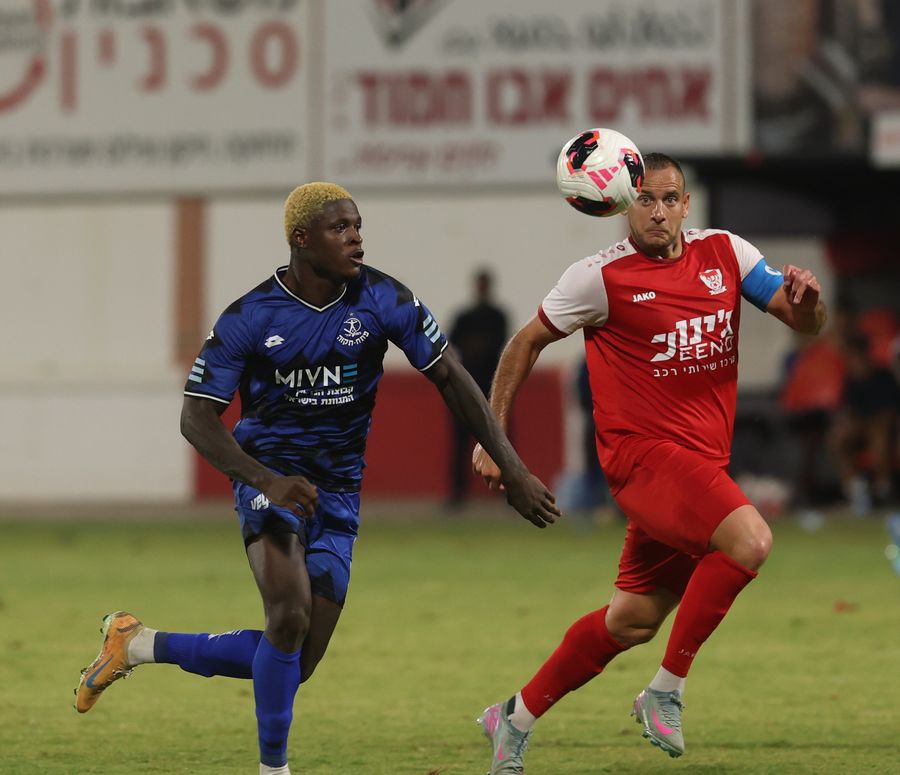Iyad Abu Abaid (Bnei Sakhnin) heads the ball as Yves Erick Bile (Hapoel Petah Tikva) runs towards the ball