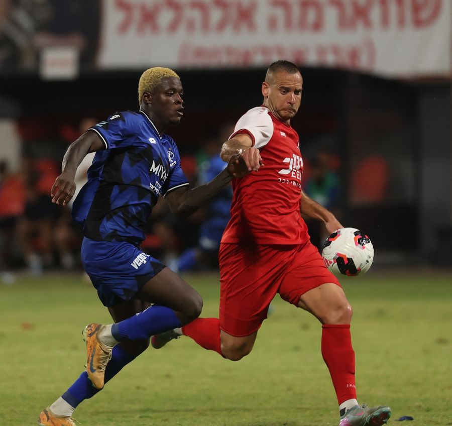 Iyad Abu Abaid (Bnei Sakhnin) runs with the ball as Yves Erick Bile (Hapoel Petah Tikva) chases the ball