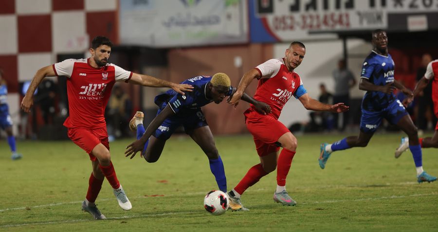 Yves Erick Bile (Hapoel Petah Tikva) controls the ball as Iyad Abu Abaid (Bnei Sakhnin) jumps to challenge for the ball