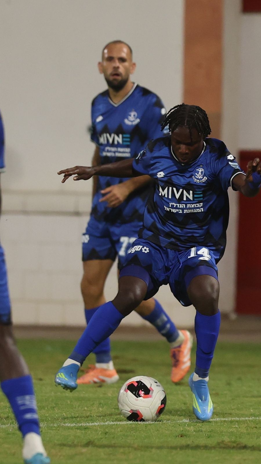 A footballer strikes the ball from outside the box