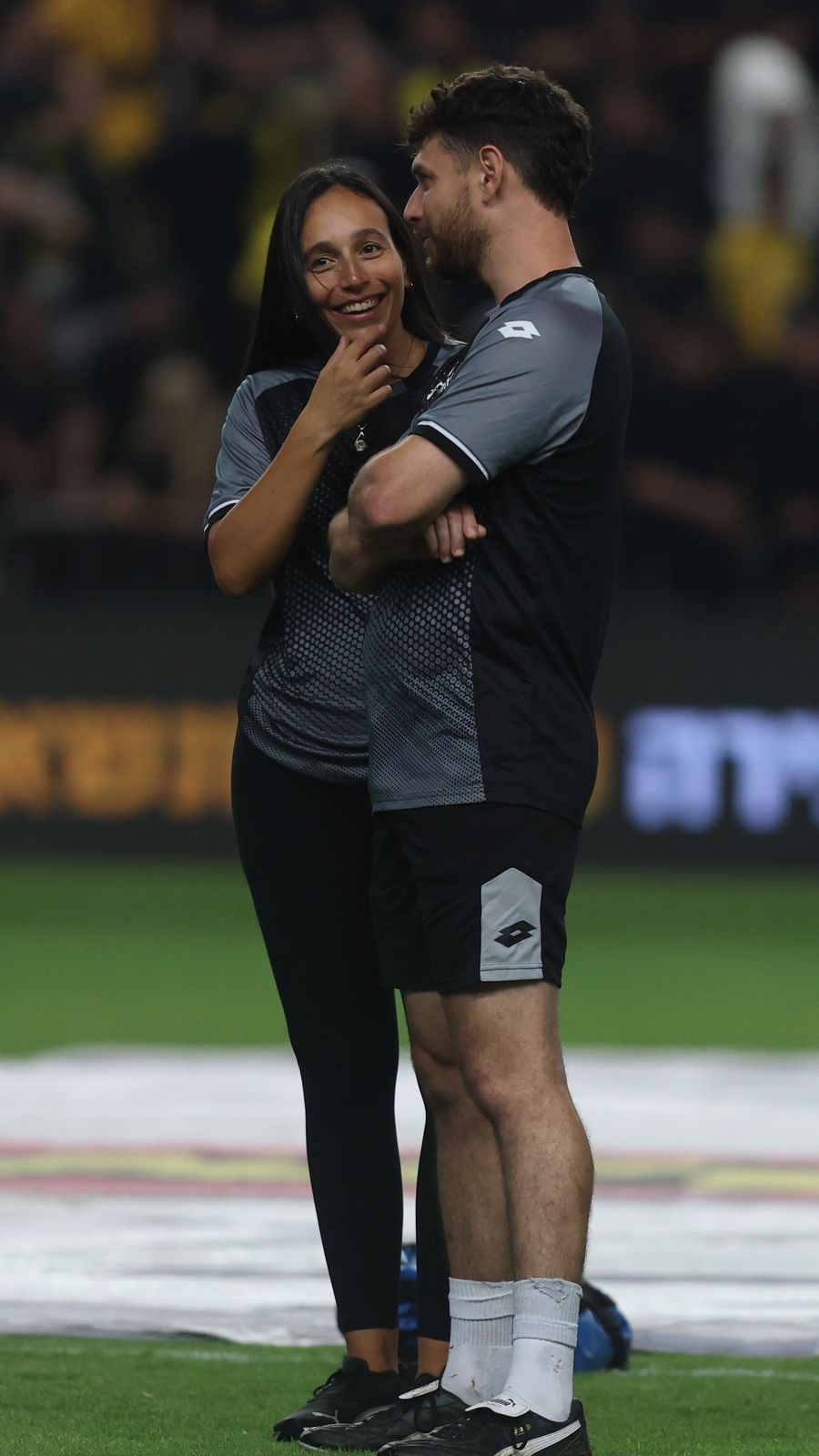 two staff members standing and talking on the field