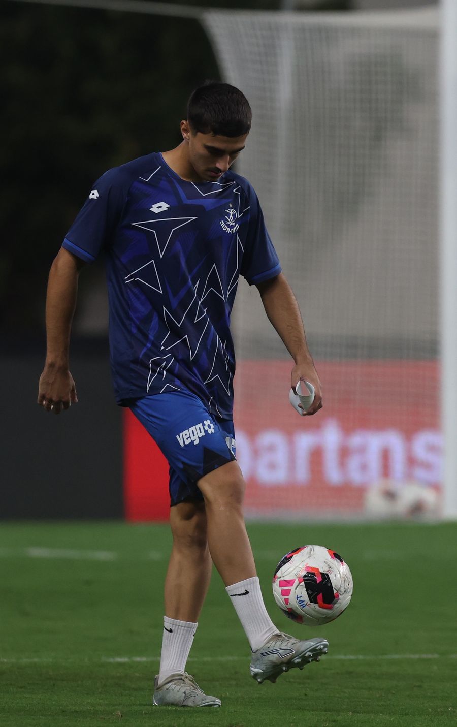 A footballer strikes the ball with his right foot