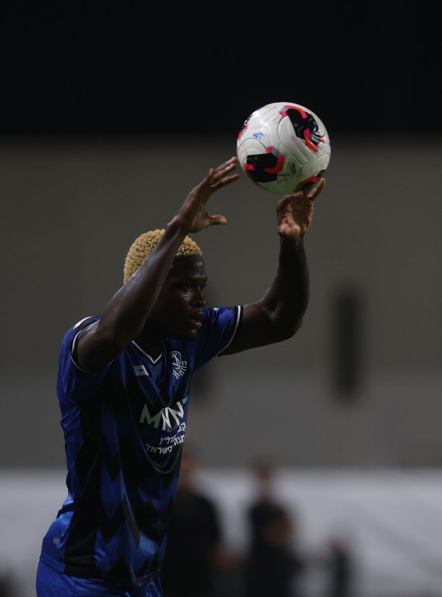 A Hapoel Petah Tikva player is catching the ball with both hands