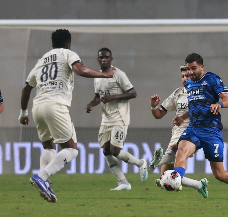 Roy Levy (#7, Hapoel Petah Tikva) strikes the ball with his right foot as Boris Enow (#40, Beitar Jerusalem) runs towards the ball