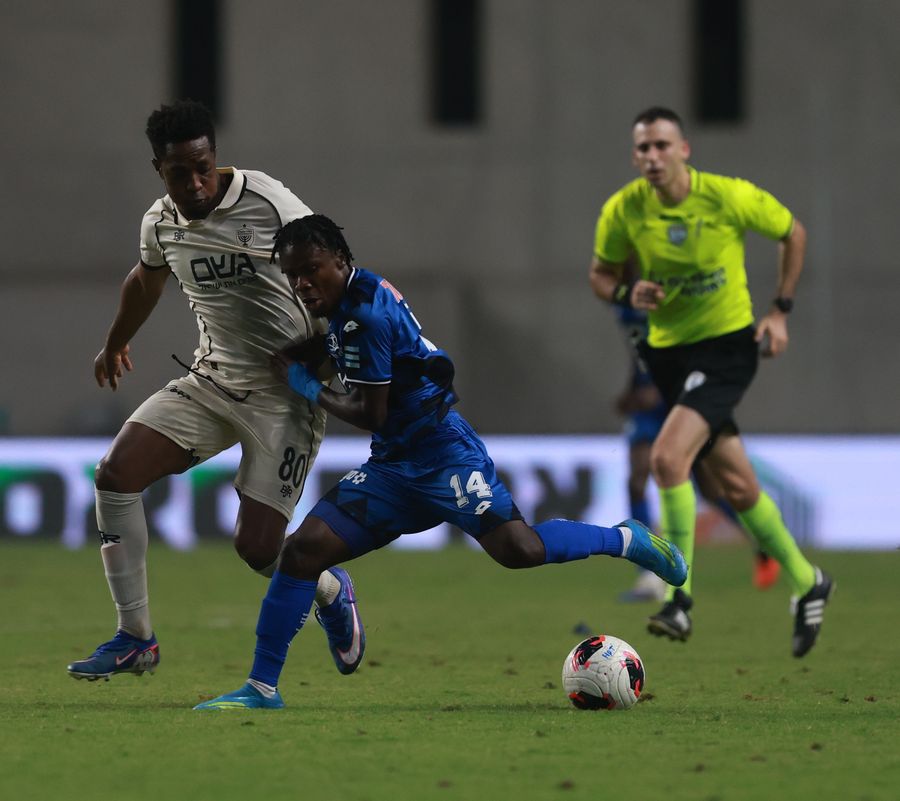 A footballer runs and attempting to get past a defender
