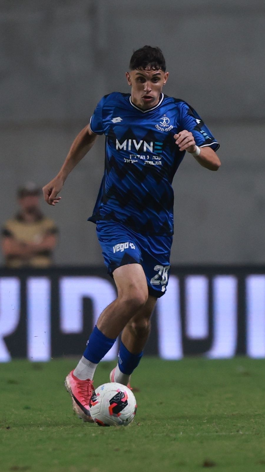 A player in a blue kit is dribbling the ball with his right foot