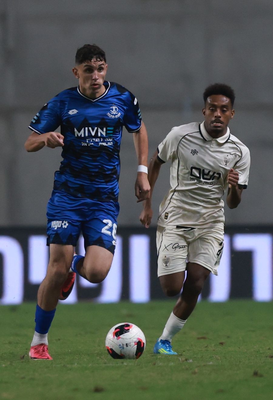 Noam Cohen (#28, Hapoel Petah Tikva) sprints with the ball as Daniel Worko (Beitar Jerusalem) runs towards the ball