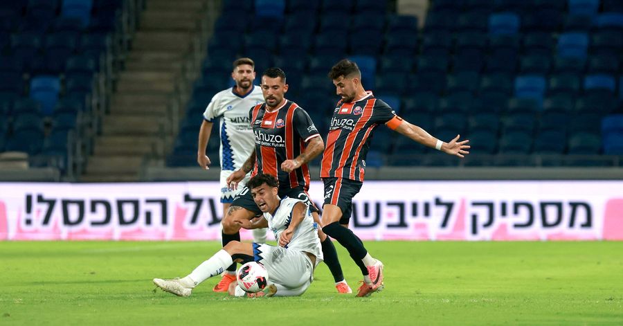 Or Israelov (Hapoel Petah Tikva) is lying on the ground with the ball at his feet