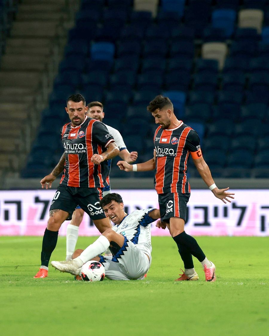 Or Israelov (Hapoel Petah Tikva) is lying on the ground with the ball at his feet, attempting to control it