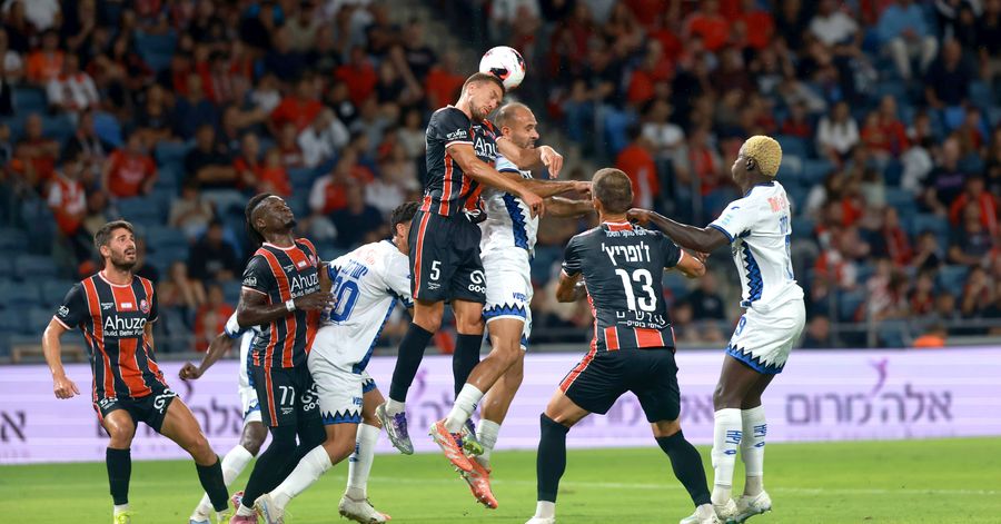 A footballer competes for an aerial ball during a match