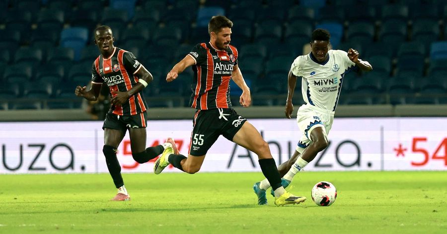 Karim Kimvuidi (Hapoel Petah Tikva) chases the ball as Naor Sabag (Hapoel Haifa) runs towards the ball