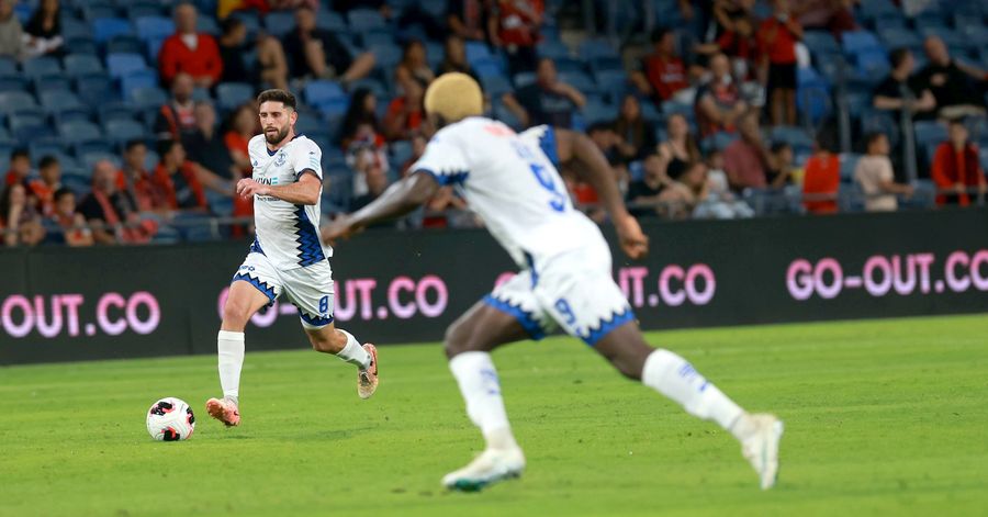 A Hapoel Petah Tikva player strikes the ball from outside the box