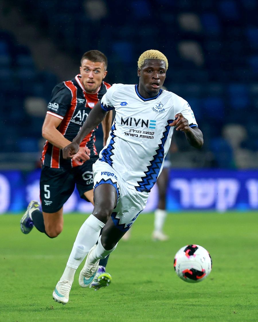 Yves Erick Bile (Hapoel Petah Tikva) runs towards the ball as Ivan Kričak (Hapoel Haifa) runs behind the player in white