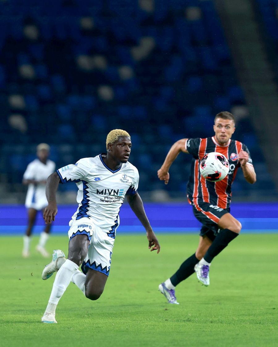 Ivan Kričak (Hapoel Haifa) controls the ball as Yves Erick Bile (Hapoel Petah Tikva) sprints down the field