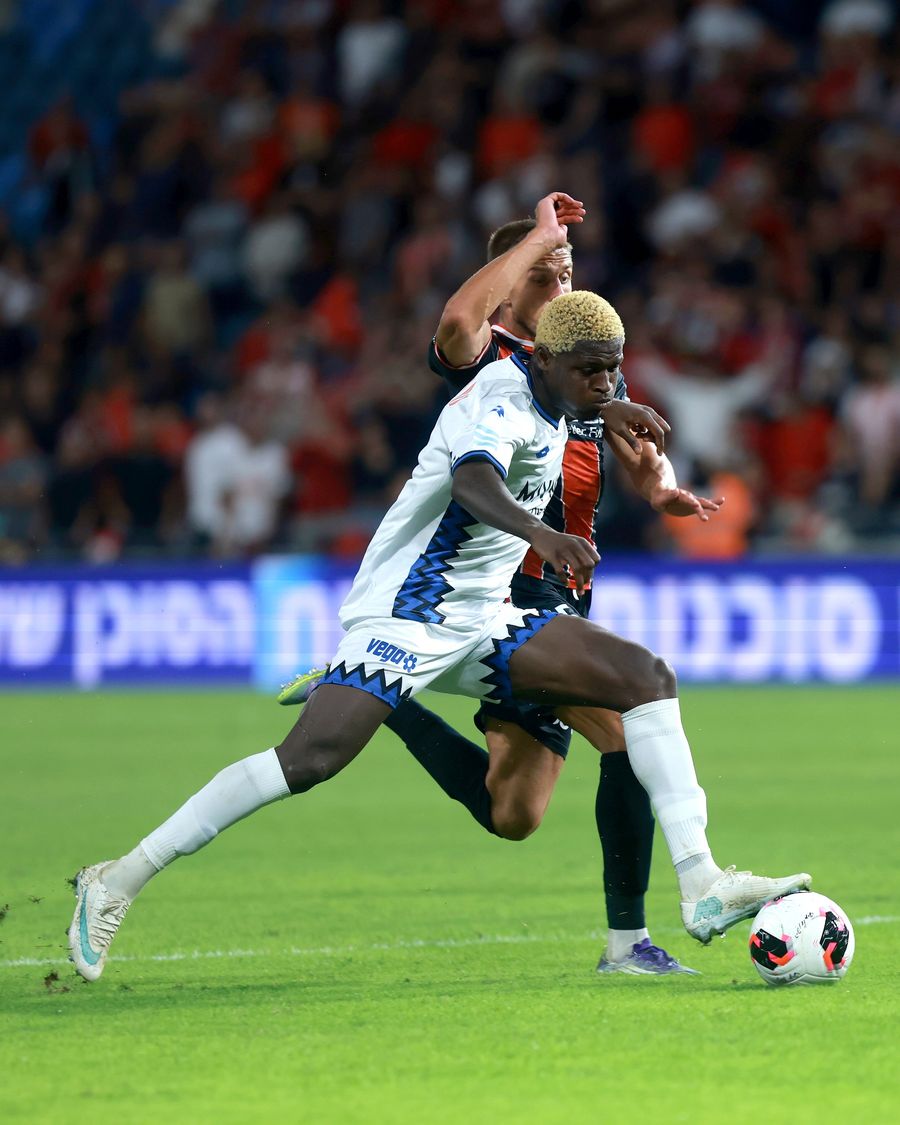 A footballer dribbles the ball past an opponent