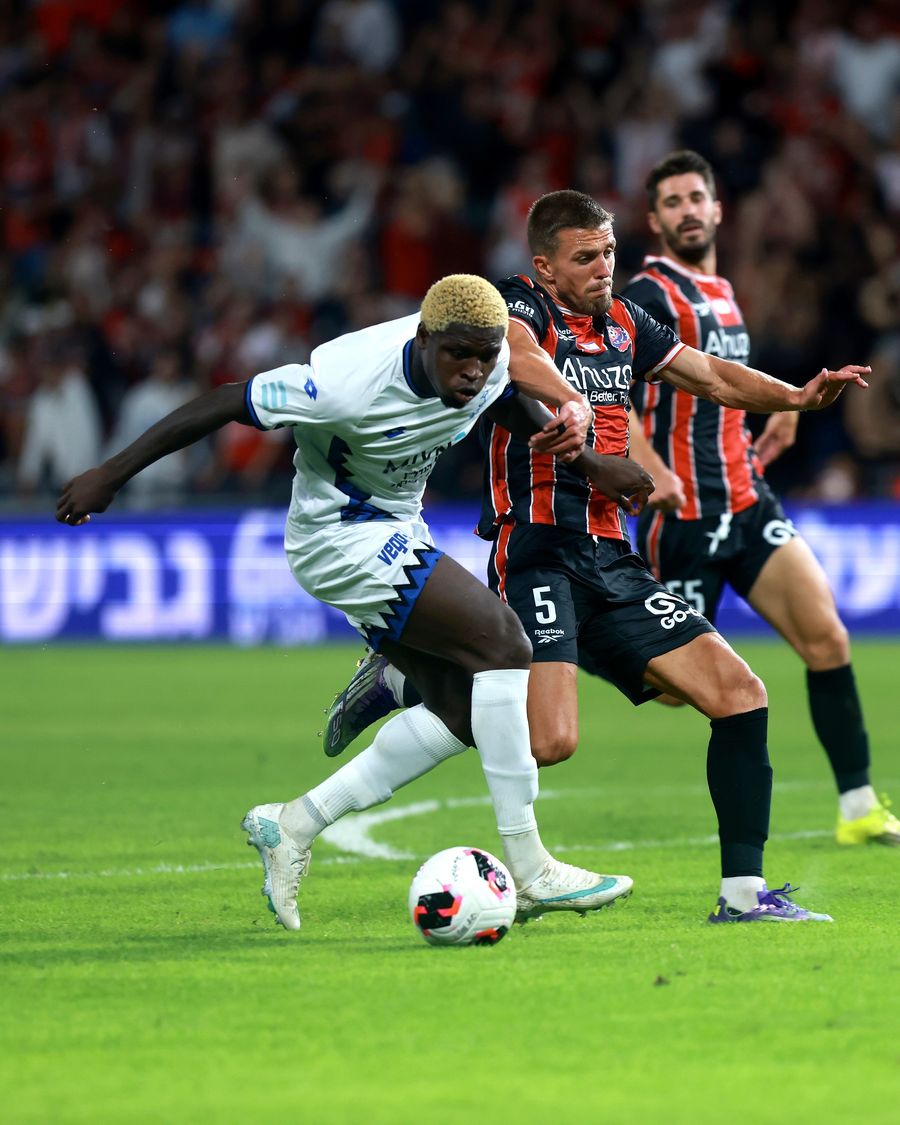 Yves Erick Bile (Hapoel Petah Tikva) runs with the ball as Naor Sabag (Hapoel Haifa) is reaching out