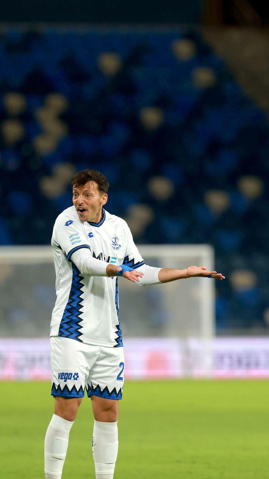 A Hapoel Petah Tikva player is gesturing with both arms outstretched