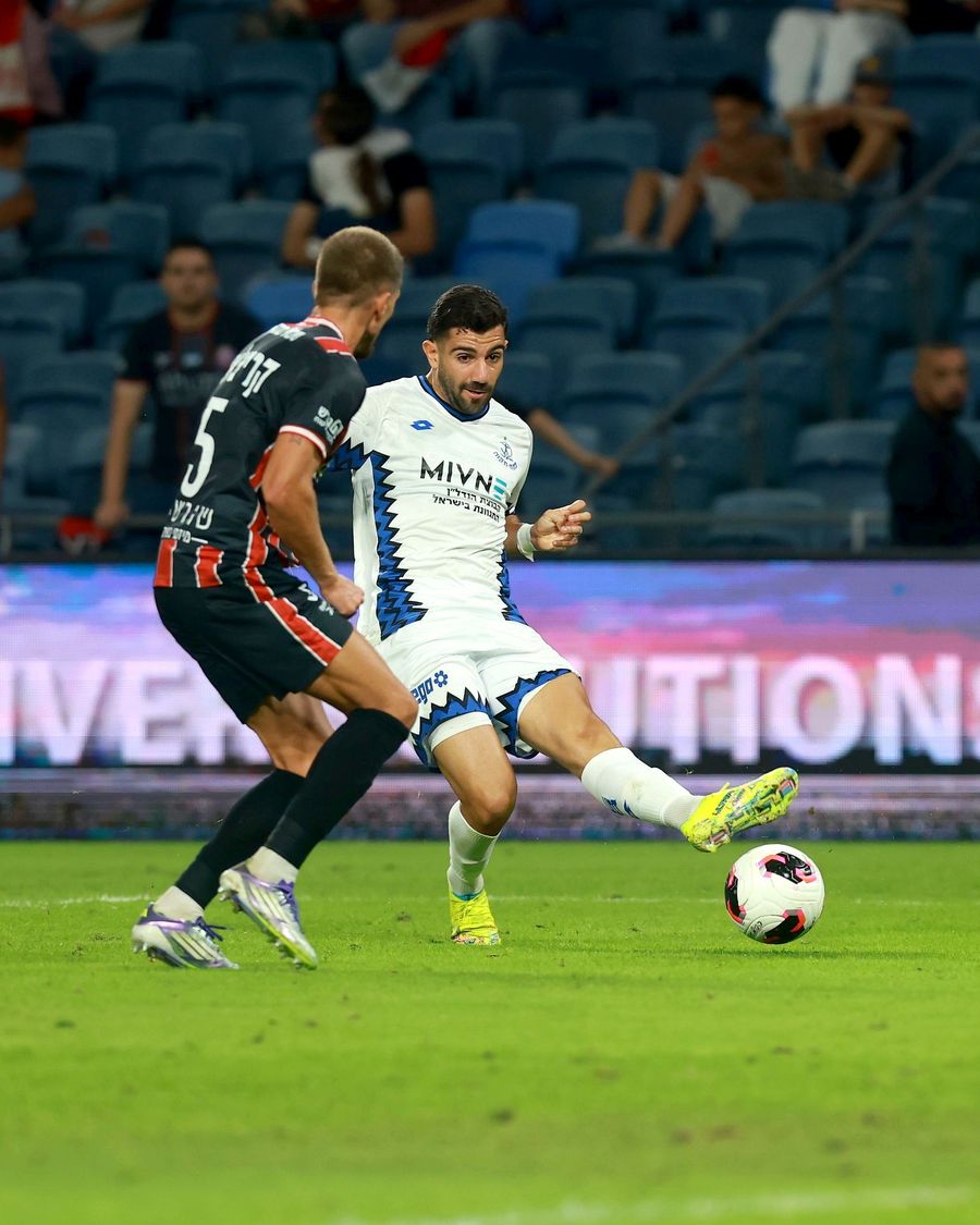 A footballer strikes the ball with his right foot