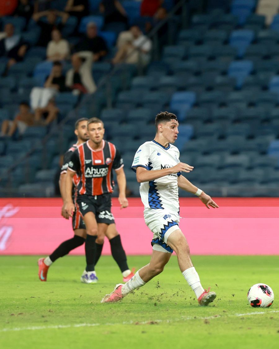 A Hapoel Petah Tikva player strikes the ball from outside the box