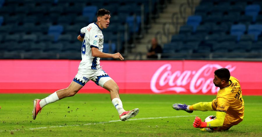 A footballer dives to block the ball
